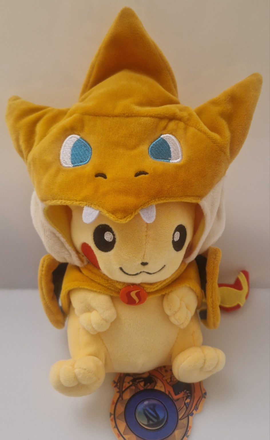 Front view of Pikachu plush wearing removable Charizard-style costume
