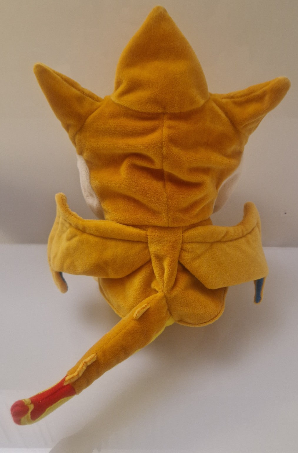 Rear view of Pikachu plush wearing removable Charizard-style costume